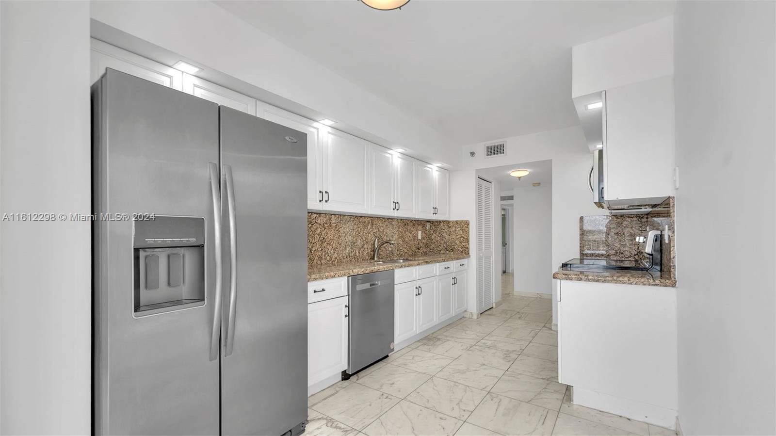 9341 Collins Avenue, Unit 707 Surfside, FL 33154 - Photo 6 of 55 a large kitchen with cabinets and stainless steel appliances