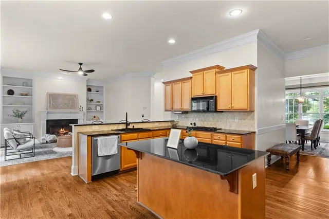 a kitchen with stainless steel appliances granite countertop a sink stove and wooden cabinets