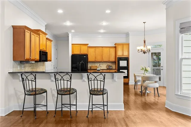 a kitchen with stainless steel appliances granite countertop a stove top oven a sink a dining table and chairs with wooden floor