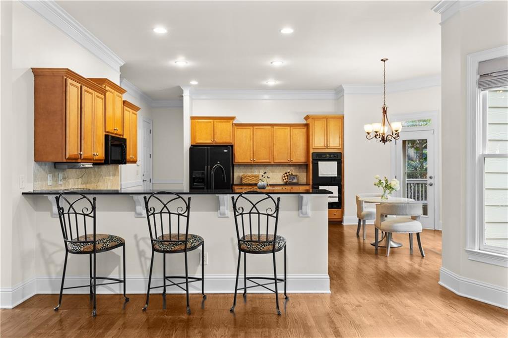 5765 Bailey Ridge Court Johns Creek, GA 30097 - Photo 8 of 51 a kitchen with stainless steel appliances granite countertop a stove top oven a sink a dining table and chairs with wooden floor