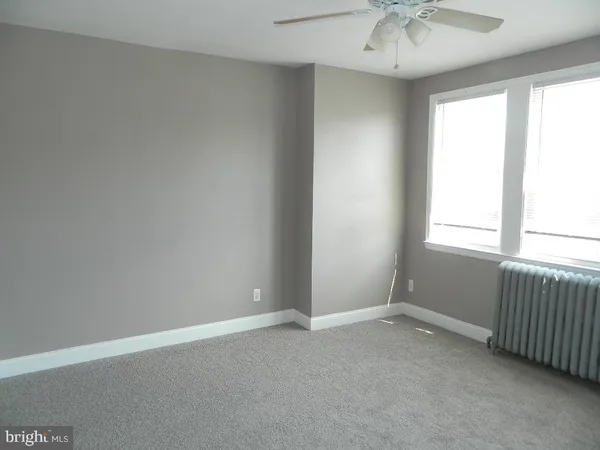 an empty room with a chandelier fan and windows