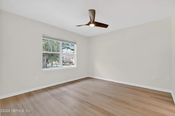a view of an empty room with wooden floor and a window