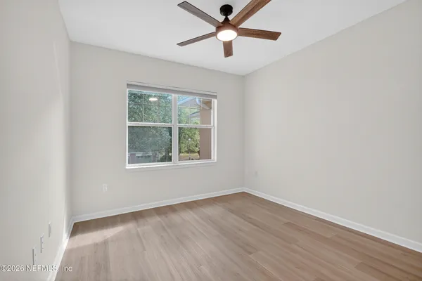 an empty room with wooden floor ceiling fan and windows