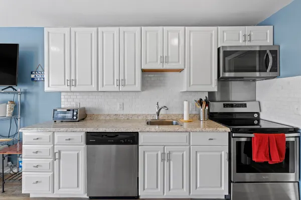 a kitchen with stainless steel appliances granite countertop a sink stove and microwave