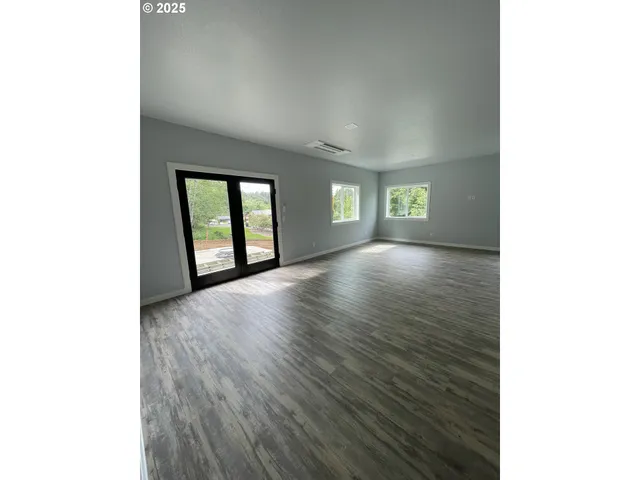 a view of an empty room with window and wooden floor