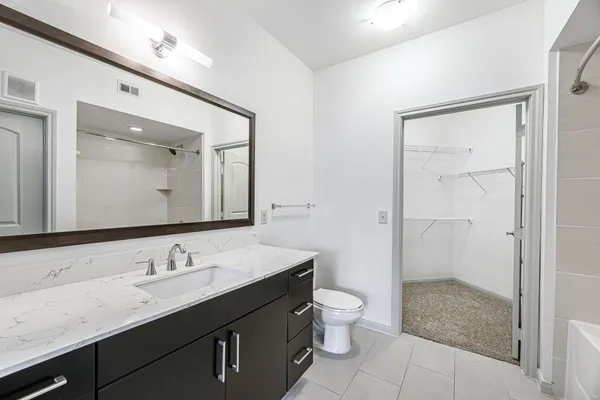 a bathroom with a granite countertop sink toilet a mirror a vanity and shower