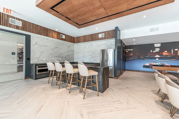 a dining hall with stainless steel appliances kitchen island granite countertop a table chairs and a large window