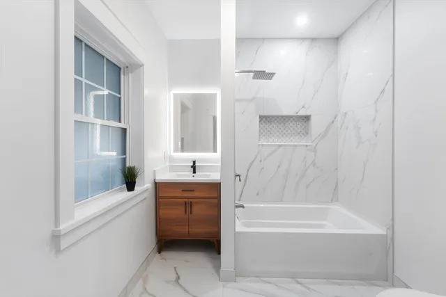 a bathroom with a bathtub a mirror a shower and vanity