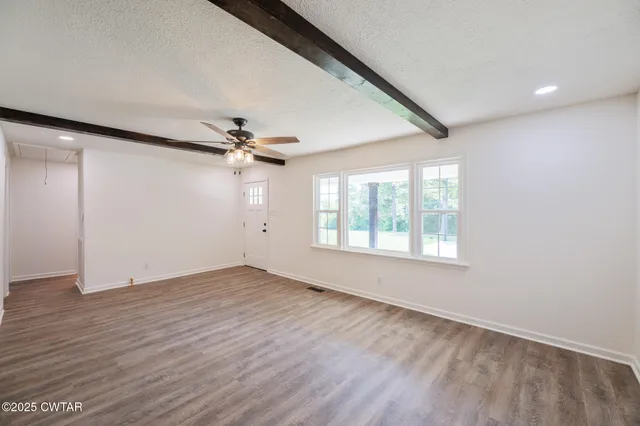 a view of empty room with wooden floor and ceiling fan