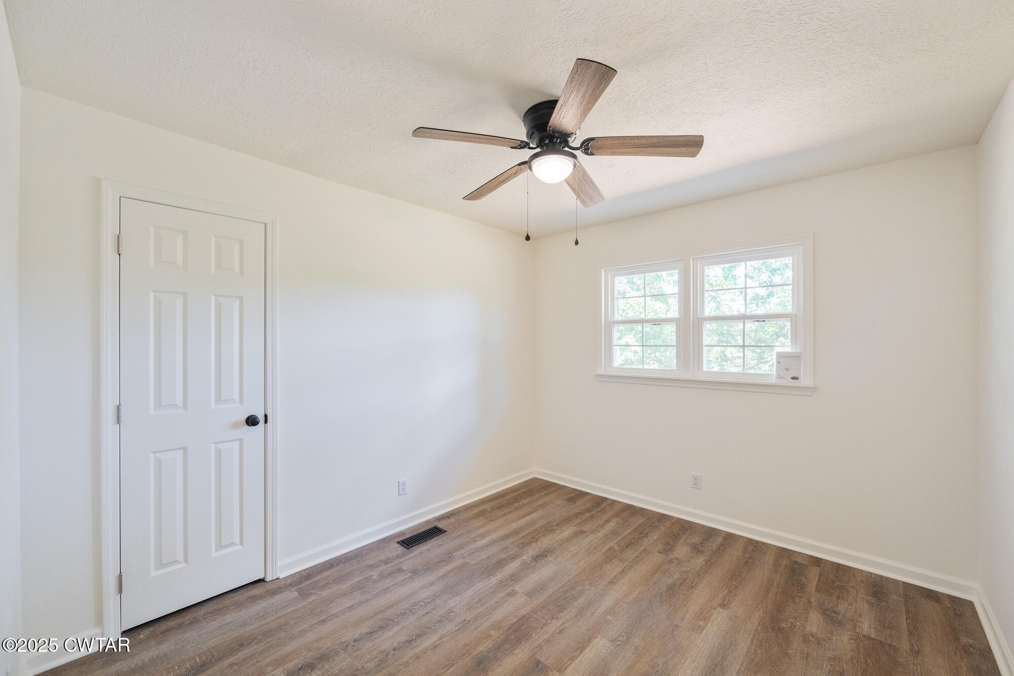 7371 Brooksie Thompson Road Bath Springs, TN 38311 - Photo 13 of 25 a view of empty room with wooden floor and fan