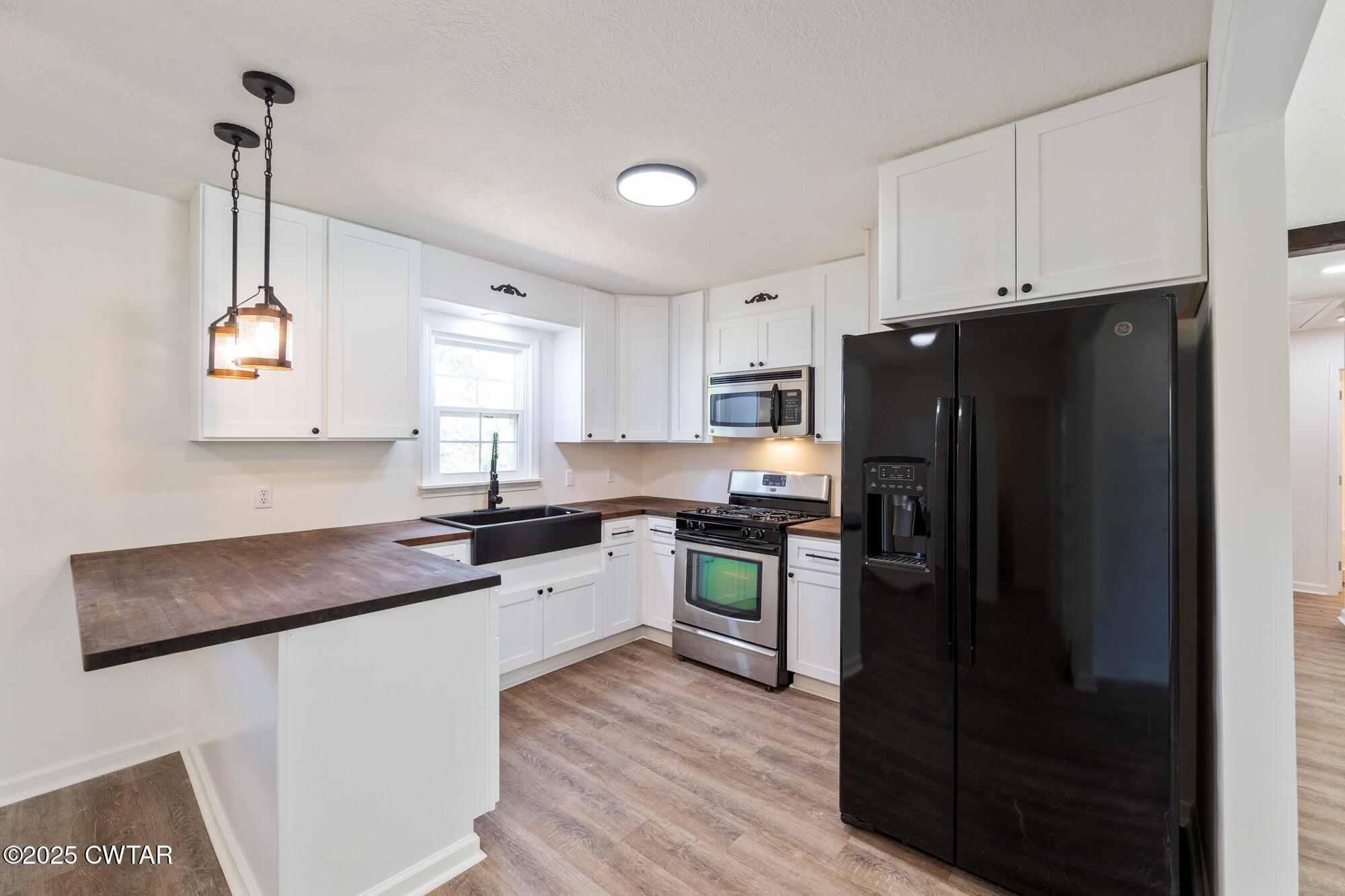 7371 Brooksie Thompson Road Bath Springs, TN 38311 - Photo 9 of 25 a kitchen with a refrigerator a sink dishwasher a stove and white cabinets with wooden floor