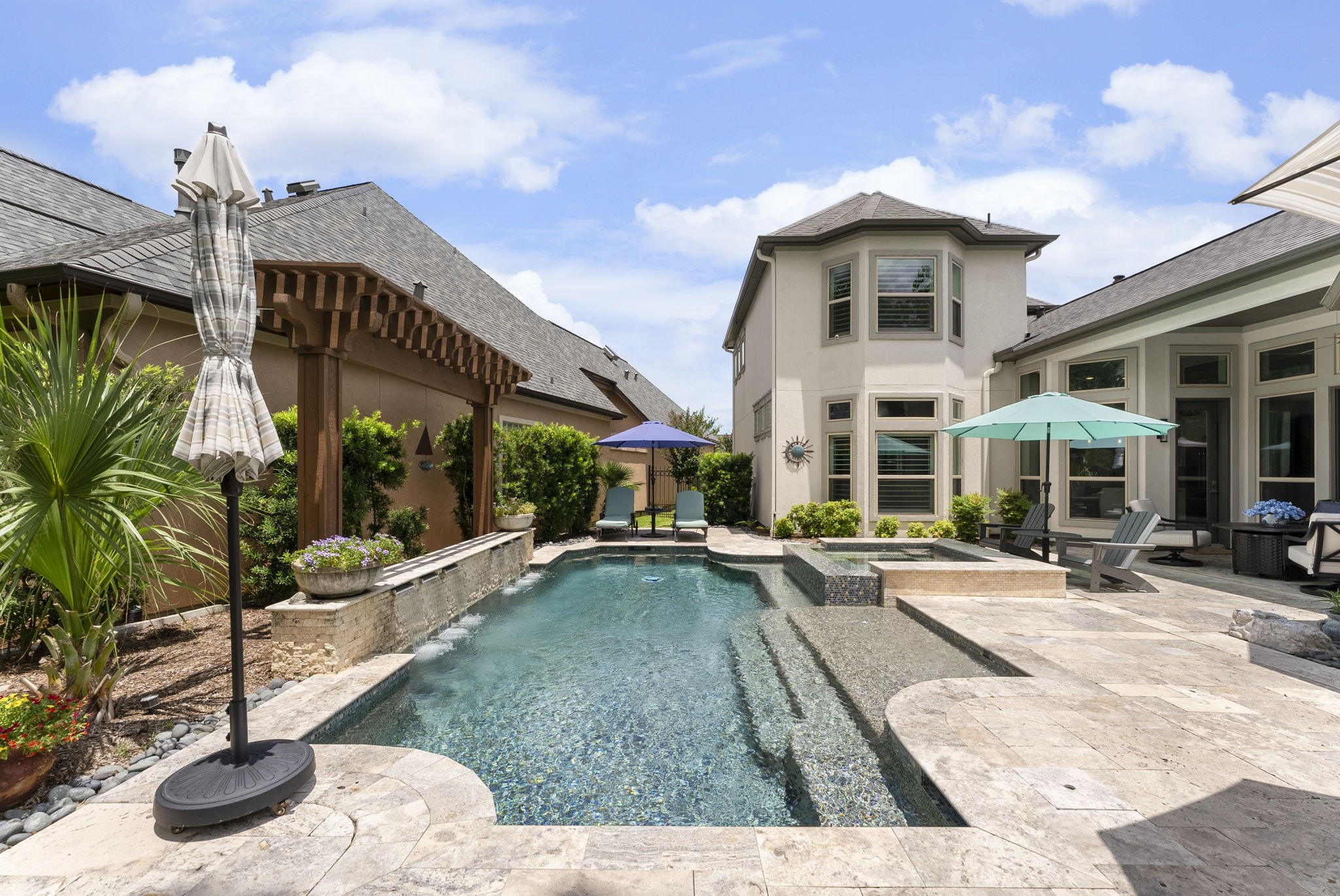 25607 Muirfield Bend Court Spring, TX 77389 - Photo 30 of 30 Thoughtfully crafted backyard sanctuary with a pool, spa, tanning shelf, cascading water wall, and multiple seating areas, offering the feel of a private resort just steps from home.