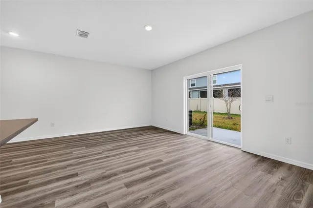 a view of an empty room with wooden floor and windows