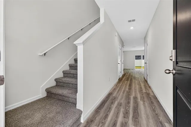 a view of a hallway with wooden floor and staircase