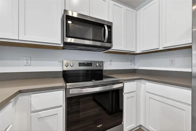 a kitchen with stainless steel appliances granite countertop white cabinets a sink and dishwasher