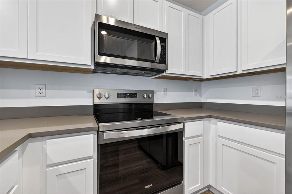31264 Paper Birch Street Wesley Chapel, FL 33545 - Photo 6 of 32 a kitchen with stainless steel appliances granite countertop white cabinets a sink and dishwasher