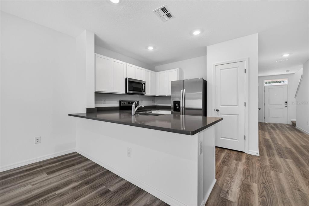 31264 Paper Birch Street Wesley Chapel, FL 33545 - Photo 8 of 32 a kitchen with granite countertop a sink stove and refrigerator