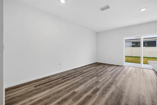 a view of empty room with wooden floor and fence