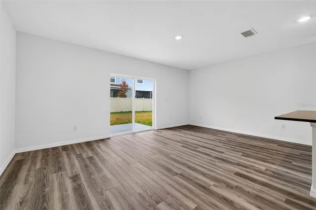 a view of empty room with wooden floor and windows