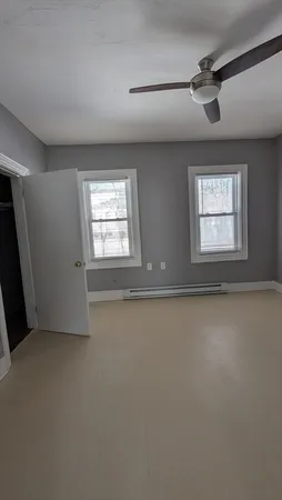 an empty room with windows and fan