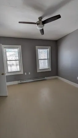 an empty room with windows and ceiling fan