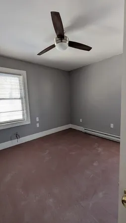 an empty room with a ceiling fan and window
