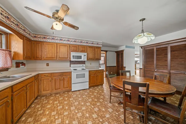 a open kitchen with stainless steel appliances granite countertop a stove a sink dishwasher a dining table and chairs with wooden floor