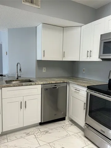 a kitchen with granite countertop white cabinets and stainless steel appliances