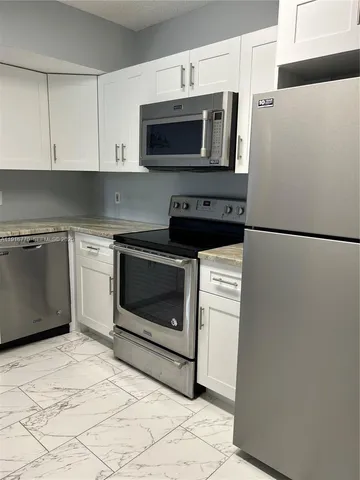 a kitchen with stainless steel appliances a stove a microwave and white cabinets