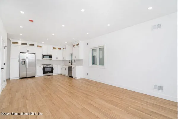 a view of a kitchen with stainless steel appliances wooden floor and windows