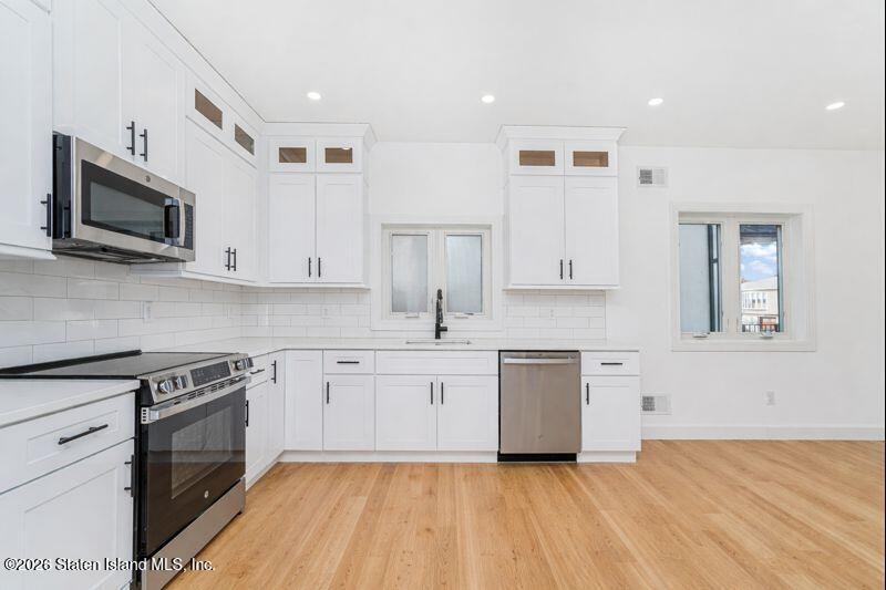 911 Rathbun Avenue Staten Island, NY 10309 - Photo 7 of 30 a kitchen with stainless steel appliances granite countertop a stove top oven a sink dishwasher and white cabinets with wooden floor