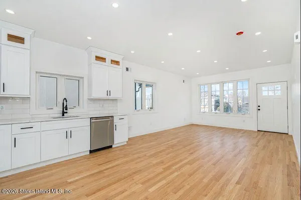 a large kitchen with a wooden floor and white cabinets
