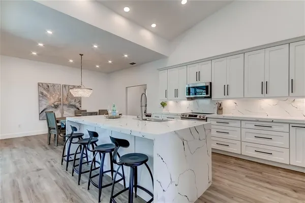 a kitchen with stainless steel appliances kitchen island granite countertop a table chairs sink and cabinets