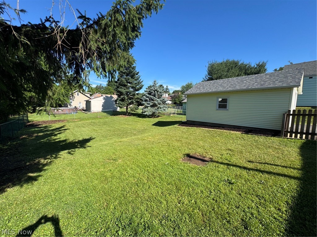 145 Anna Avenue Northwest Canton, OH 44708 - Photo 26 of 27 Expansive backyard featuring a detached garage with light green siding, a gray shingle roof, and a single window