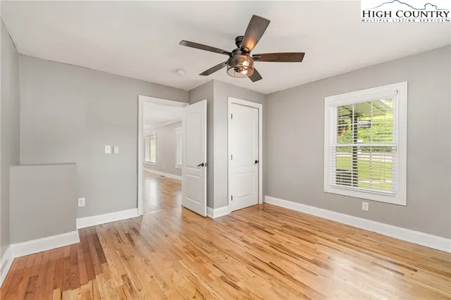 a view of an empty room with a window and wooden floor