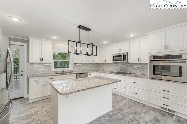 a kitchen with stainless steel appliances granite countertop a sink stove a refrigerator and white cabinets