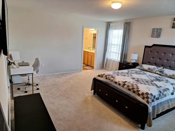 a bedroom with a bed and a dresser with rug