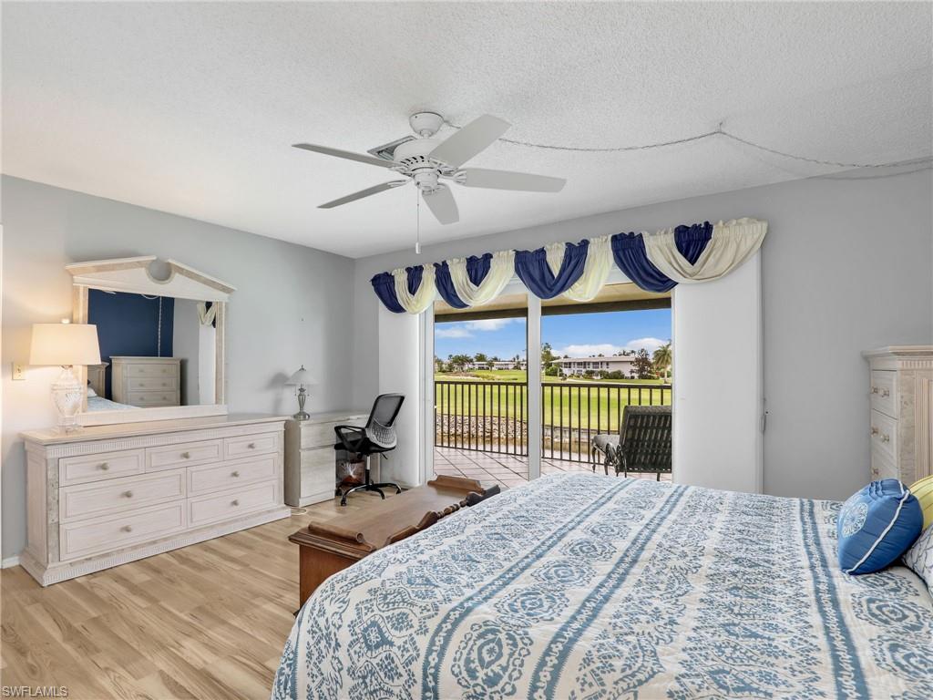 119 Harrison Road, Unit 16 Naples, FL 34112 - Photo 11 of 26 Bedroom featuring access to outside, light wood-style flooring, a ceiling fan, and a textured ceiling