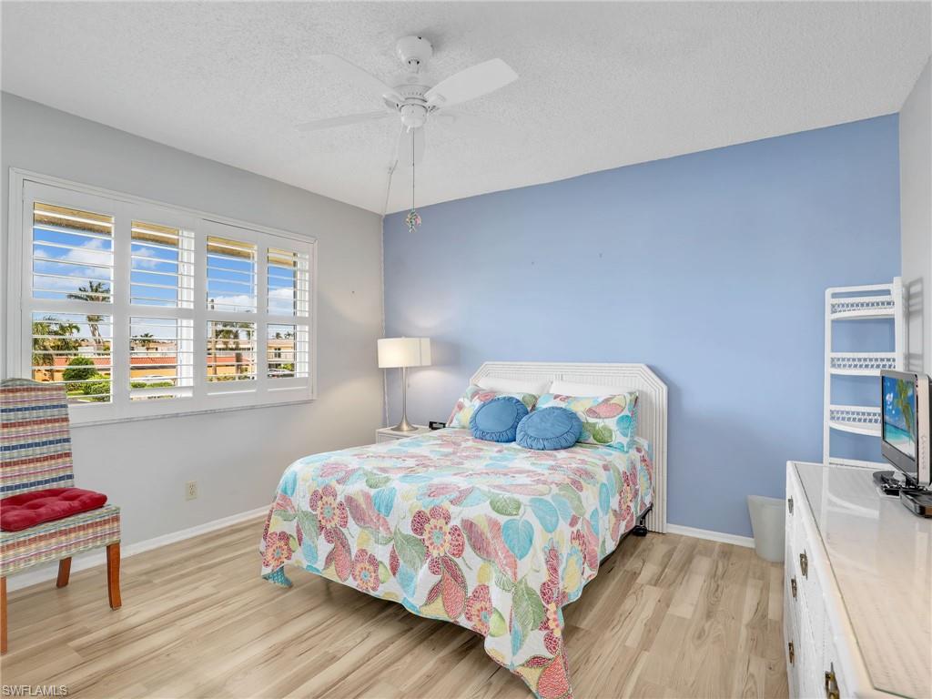 119 Harrison Road, Unit 16 Naples, FL 34112 - Photo 14 of 26 Bedroom featuring light wood finished floors, a textured ceiling, and a ceiling fan