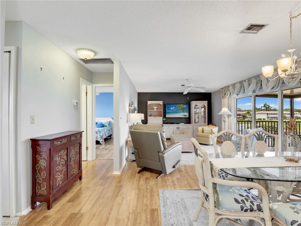 119 Harrison Road, Unit 16 Naples, FL 34112 - Photo 6 of 26 Dining space with a chandelier, light wood-style flooring, a textured ceiling, and a ceiling fan