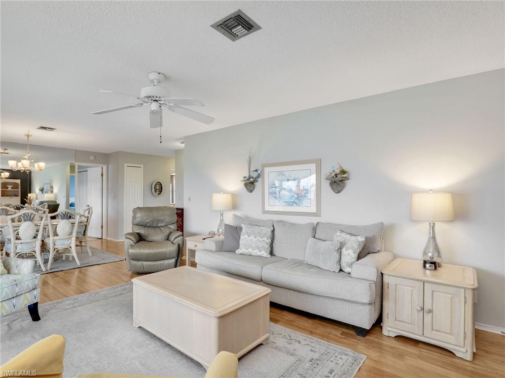 119 Harrison Road, Unit 16 Naples, FL 34112 - Photo 8 of 26 Living room featuring light wood-type flooring, a ceiling fan, a chandelier, and a textured ceiling