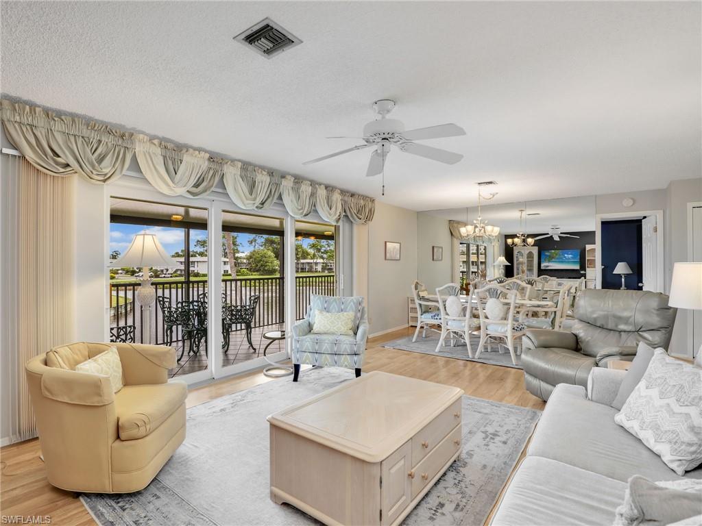119 Harrison Road, Unit 16 Naples, FL 34112 - Photo 9 of 26 Living area with ceiling fan, light wood-type flooring, and a chandelier