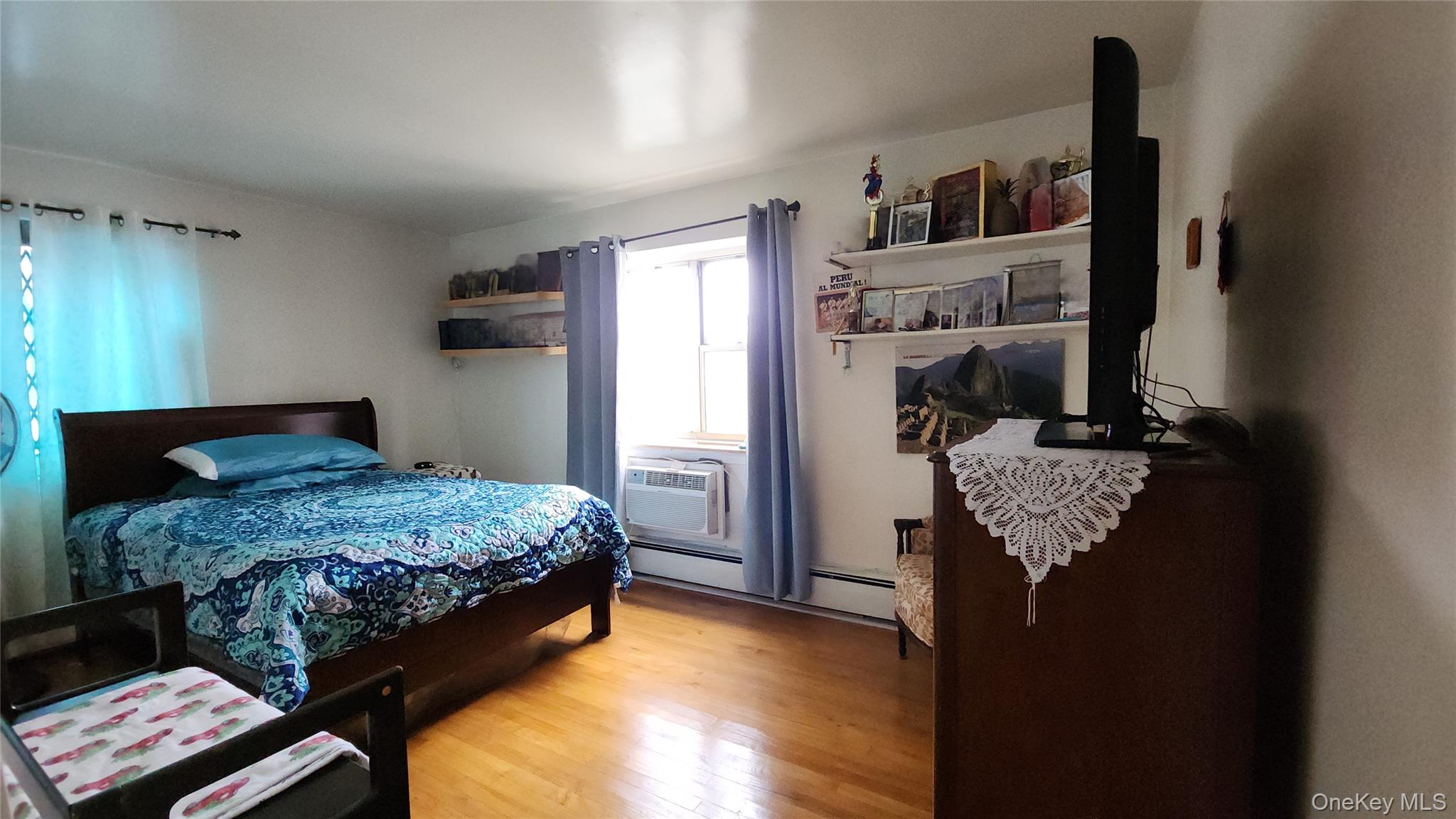 99-10 60th Avenue, Unit 3H Queens, NY 11368 - Photo 15 of 25 a bedroom with a bed and wooden floor