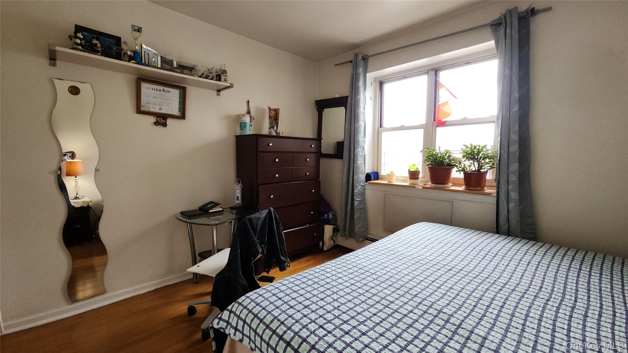 99-10 60th Avenue, Unit 3H Queens, NY 11368 - Photo 17 of 25 a bedroom with a bed and wooden floor