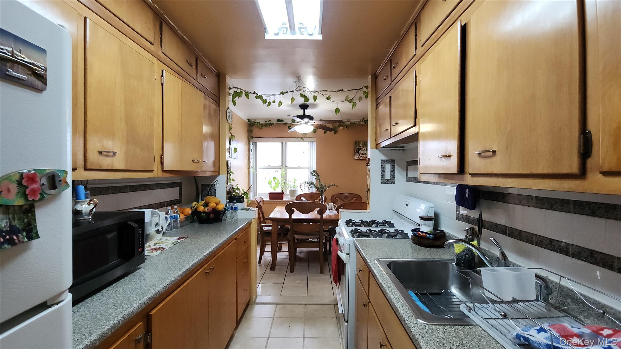 99-10 60th Avenue, Unit 3H Queens, NY 11368 - Photo 3 of 25 a kitchen filled counter top space a sink stove and cabinets