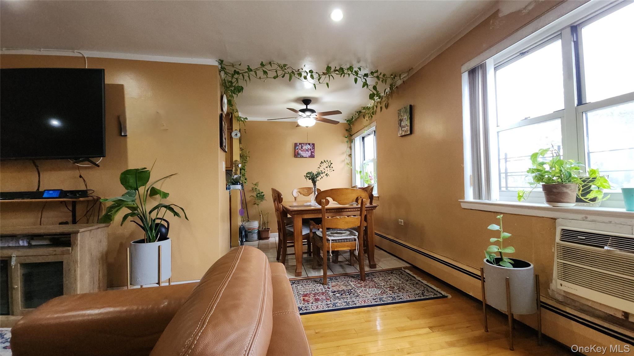 99-10 60th Avenue, Unit 3H Queens, NY 11368 - Photo 8 of 25 a living room with furniture a chandelier and a flat screen tv