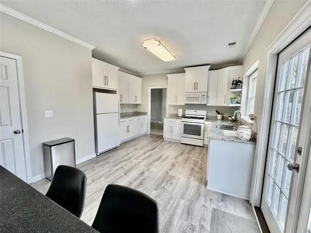 a kitchen with stainless steel appliances granite countertop a refrigerator stove oven and white cabinets