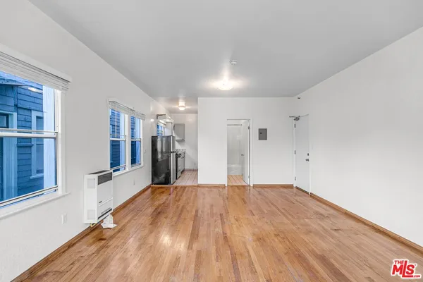 a view of a big room with wooden floor and windows