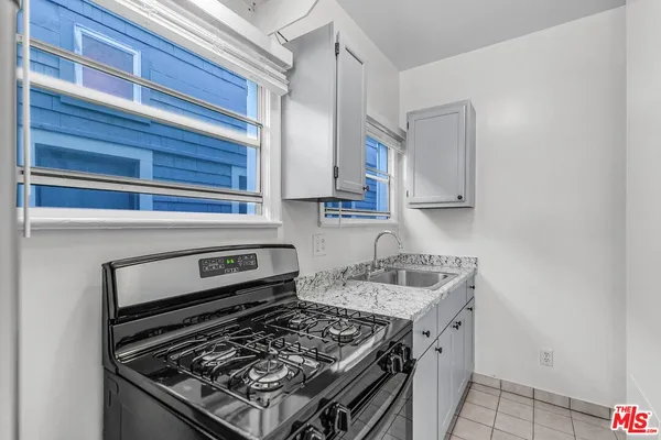 a kitchen with granite countertop a sink stove and cabinets