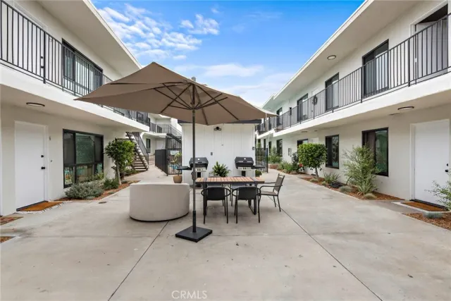a view of a patio with couches table and chairs under an umbrella